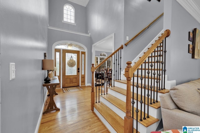 entrance foyer featuring a towering ceiling and light wood-type flooring