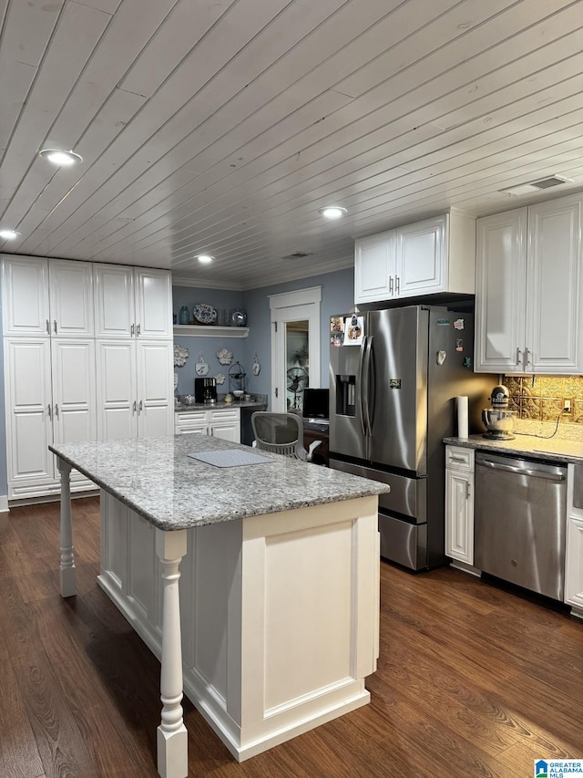 kitchen featuring a kitchen island, appliances with stainless steel finishes, white cabinetry, a breakfast bar area, and light stone countertops