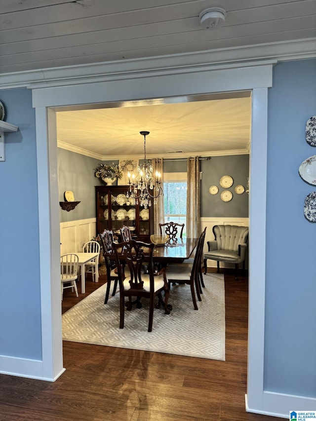 dining space featuring crown molding, dark wood-type flooring, and a notable chandelier