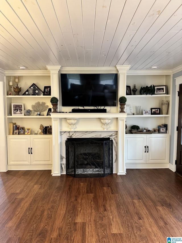 unfurnished living room with a fireplace, crown molding, dark wood-type flooring, wooden ceiling, and built in shelves