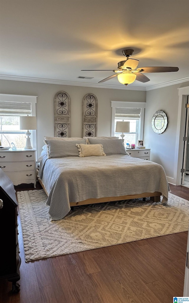 bedroom featuring crown molding, visible vents, wood finished floors, and a ceiling fan