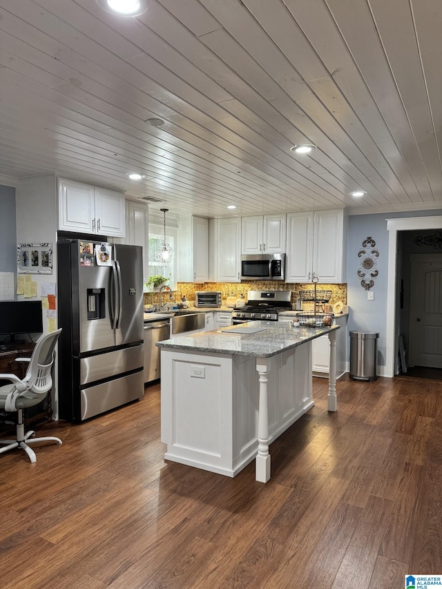 kitchen featuring a kitchen island, white cabinets, hanging light fixtures, light stone counters, and stainless steel appliances