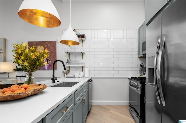 kitchen with stainless steel appliances, light countertops, hanging light fixtures, gray cabinetry, and a sink