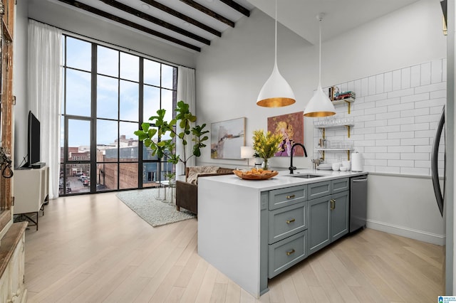 kitchen with open floor plan, decorative light fixtures, light countertops, light wood-type flooring, and a sink