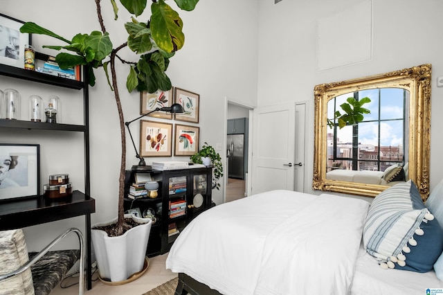 bedroom featuring a high ceiling and stainless steel fridge with ice dispenser