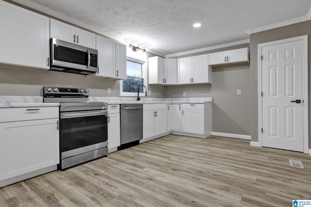 kitchen featuring appliances with stainless steel finishes, white cabinets, ornamental molding, light stone countertops, and a textured ceiling