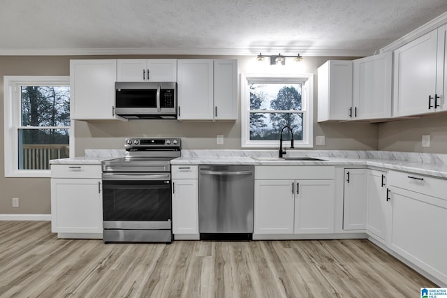 kitchen featuring white cabinetry, sink, stainless steel appliances, and light stone countertops