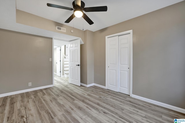 unfurnished bedroom with ceiling fan, light wood-type flooring, and a closet