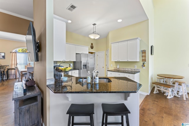 kitchen featuring pendant lighting, sink, white cabinetry, stainless steel refrigerator with ice dispenser, and kitchen peninsula