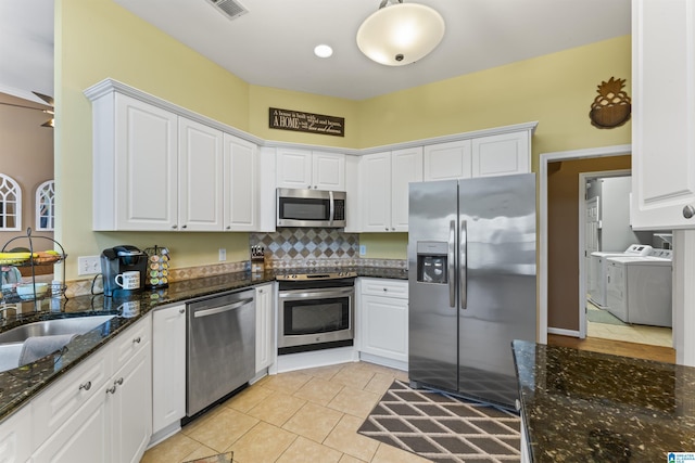 kitchen featuring white cabinetry, washing machine and dryer, dark stone counters, and appliances with stainless steel finishes