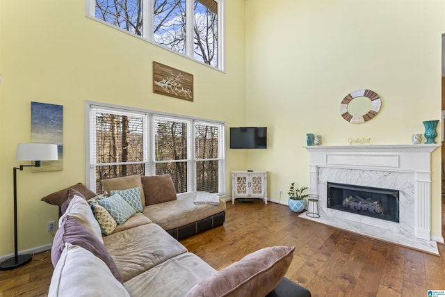 living room featuring hardwood / wood-style flooring, plenty of natural light, a premium fireplace, and a high ceiling