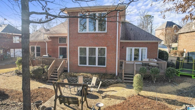 back of house featuring a wooden deck and a trampoline