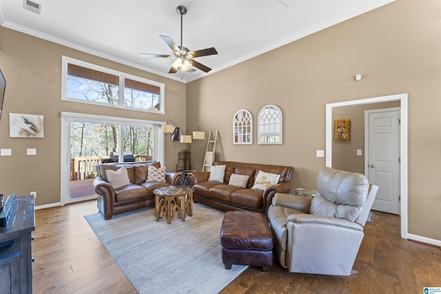 living room with crown molding, dark wood-type flooring, ceiling fan, and a towering ceiling