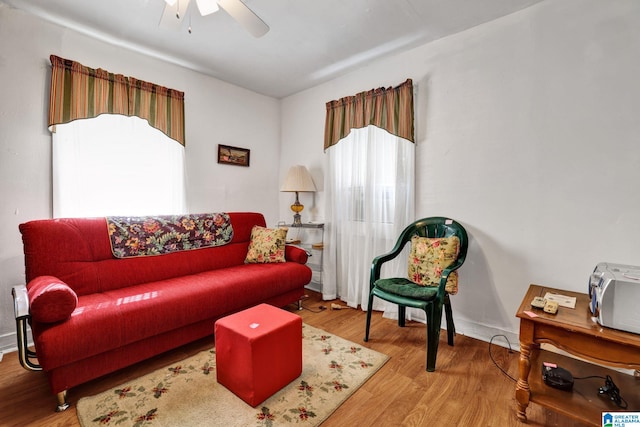 living area featuring a ceiling fan, baseboards, and wood finished floors