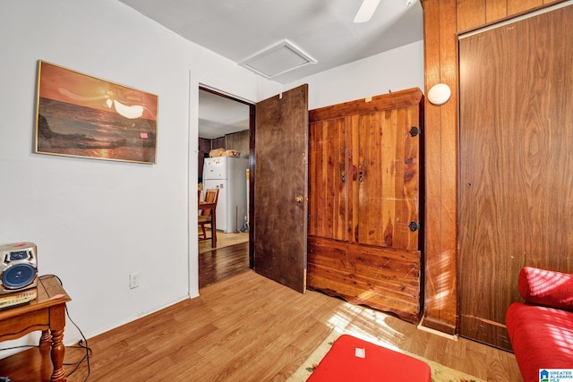 bedroom featuring light wood-type flooring, freestanding refrigerator, and attic access