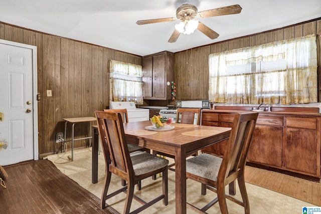 dining area featuring ceiling fan, wood walls, and independent washer and dryer