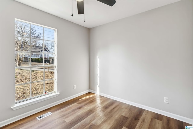 empty room featuring ceiling fan, a wealth of natural light, and light wood-type flooring