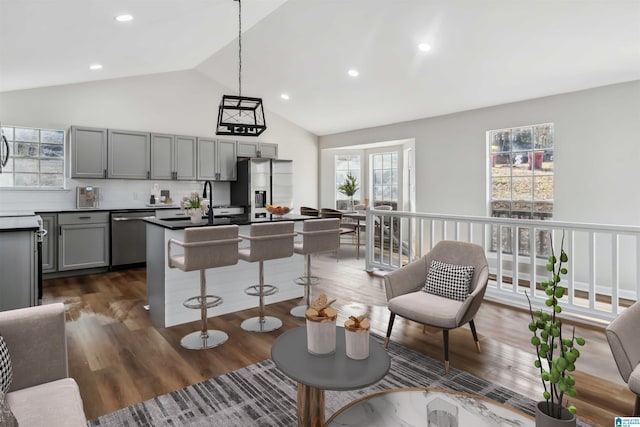 kitchen featuring lofted ceiling, gray cabinetry, hanging light fixtures, stainless steel appliances, and dark wood-type flooring