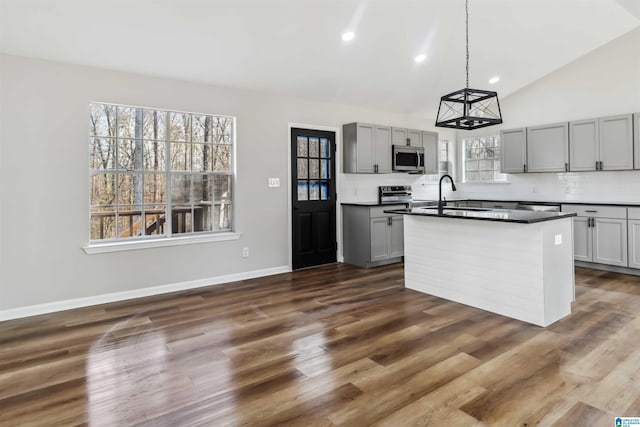 kitchen featuring pendant lighting, sink, appliances with stainless steel finishes, gray cabinetry, and vaulted ceiling