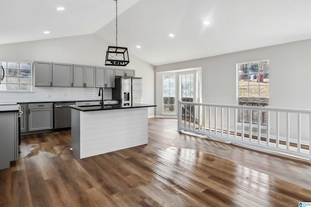 kitchen featuring gray cabinets, a kitchen island with sink, hanging light fixtures, stainless steel appliances, and dark hardwood / wood-style flooring