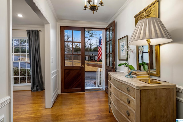 foyer with an inviting chandelier, crown molding, and hardwood / wood-style floors