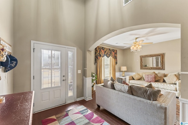 foyer with arched walkways, visible vents, a high ceiling, dark wood-type flooring, and ceiling fan