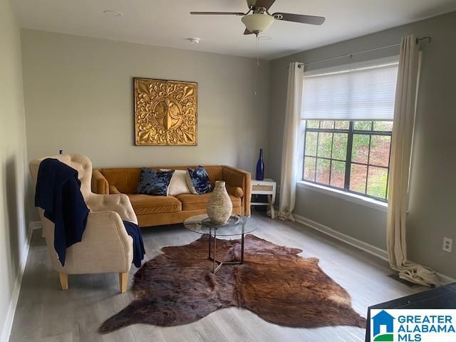 living area featuring light wood finished floors, ceiling fan, and baseboards