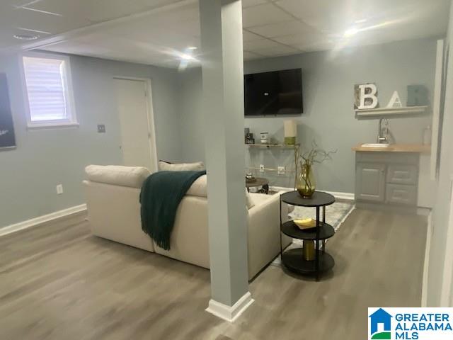 living room with a drop ceiling, wood finished floors, and baseboards