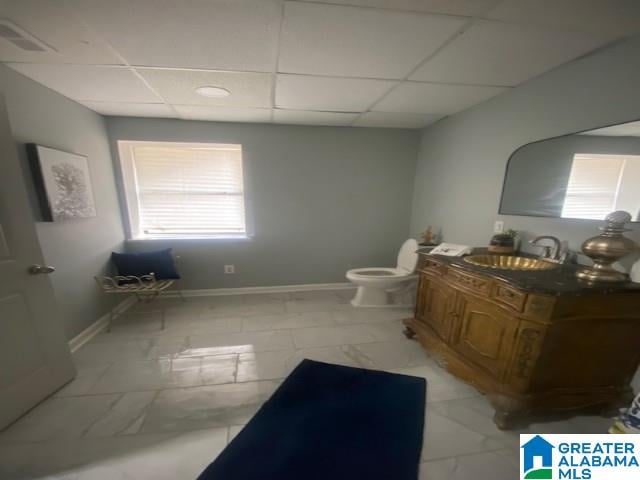 bathroom featuring a drop ceiling, vanity, and baseboards