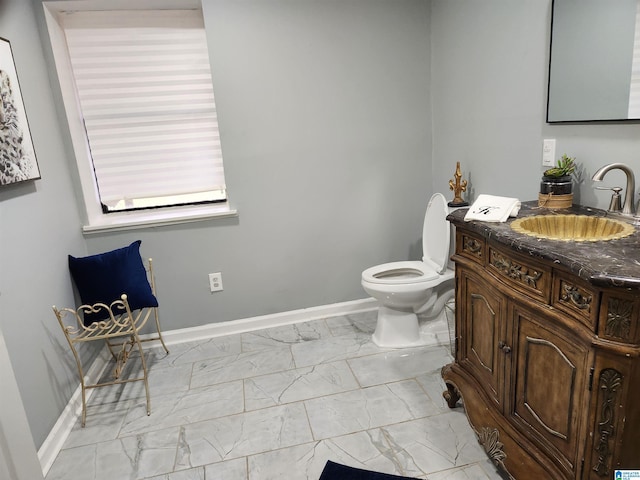 bathroom with marble finish floor, toilet, vanity, and baseboards