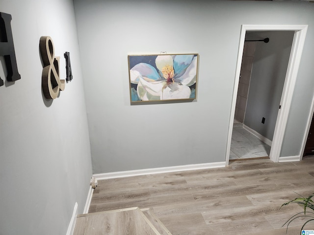 corridor featuring light wood-type flooring and baseboards