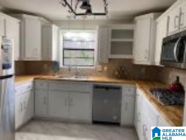 kitchen featuring light countertops, stainless steel microwave, and white cabinets