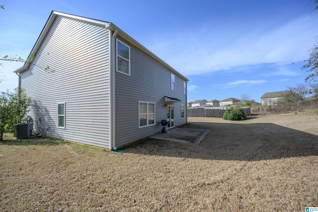 rear view of house with cooling unit and a lawn