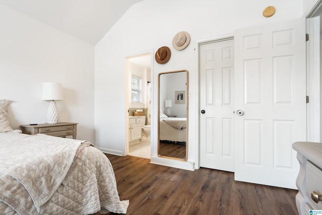 bedroom with lofted ceiling, a closet, ensuite bath, and dark hardwood / wood-style floors