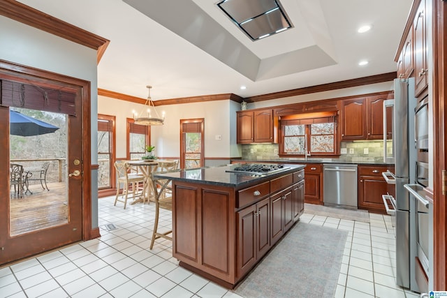 kitchen with light tile patterned flooring, appliances with stainless steel finishes, a center island, tasteful backsplash, and decorative light fixtures