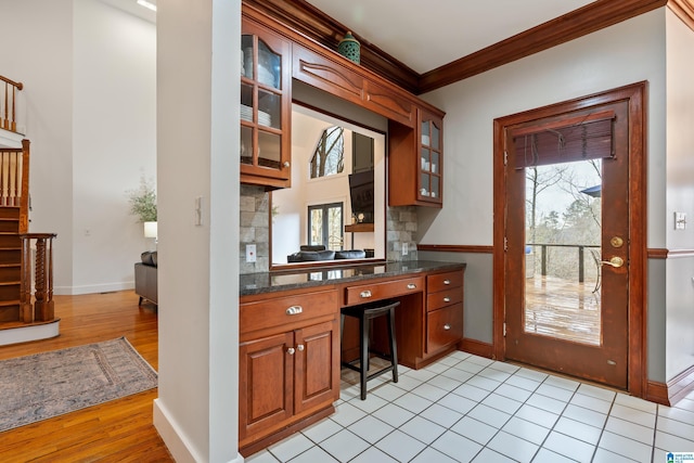 kitchen with brown cabinets, crown molding, decorative backsplash, glass insert cabinets, and plenty of natural light