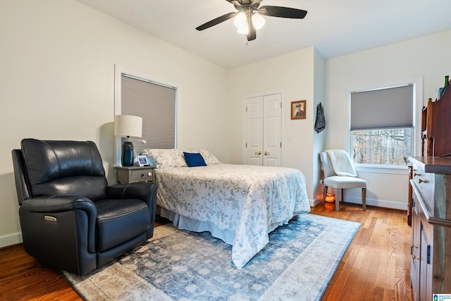 bedroom featuring a closet, wood finished floors, a ceiling fan, and baseboards