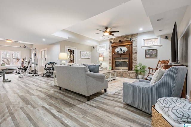 living room with light wood-style floors, recessed lighting, ceiling fan, and a stone fireplace