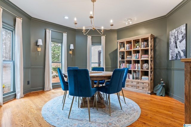 dining room with a chandelier, ornamental molding, light wood-style flooring, and baseboards