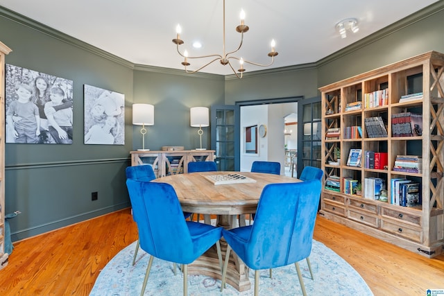 dining room with baseboards, ornamental molding, wood finished floors, and an inviting chandelier