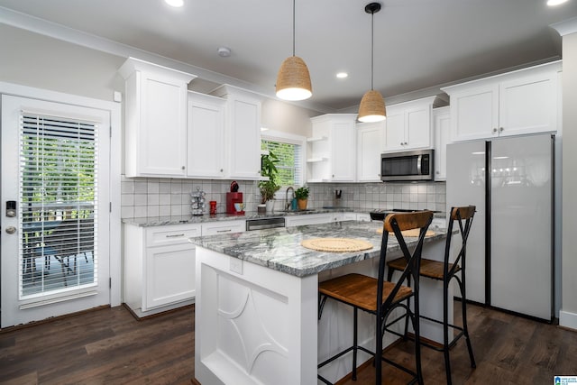 kitchen featuring white cabinetry, appliances with stainless steel finishes, pendant lighting, and light stone counters