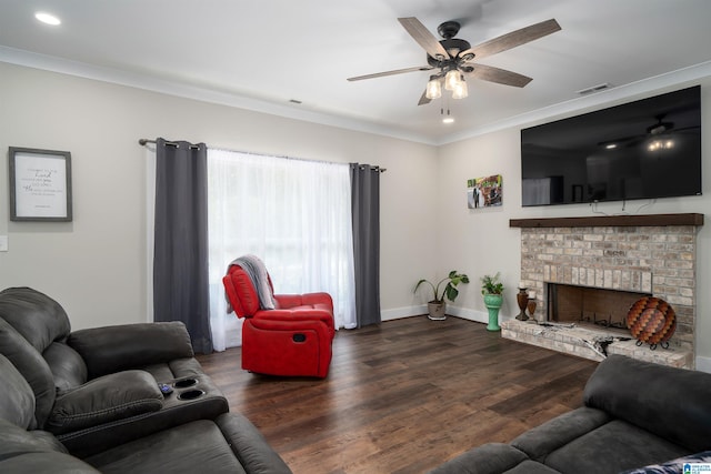 living room featuring dark wood-type flooring, ceiling fan, crown molding, and a brick fireplace