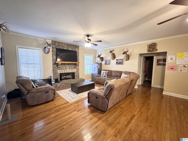 living room with a fireplace, crown molding, wood-type flooring, and ceiling fan