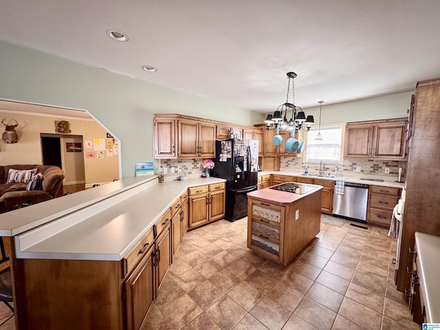 kitchen with tasteful backsplash, black appliances, a chandelier, a kitchen island, and sink