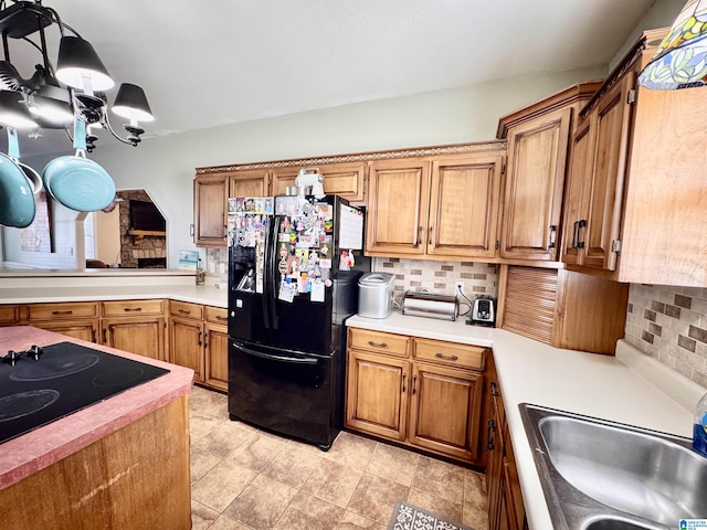 kitchen featuring sink, backsplash, black appliances, and a chandelier