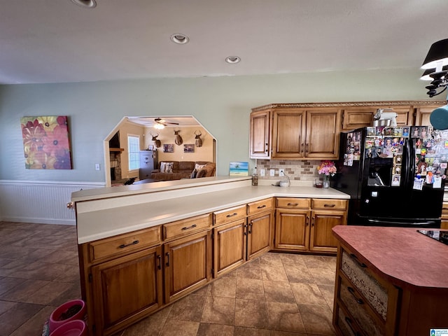 kitchen featuring black fridge, ceiling fan, kitchen peninsula, and tasteful backsplash