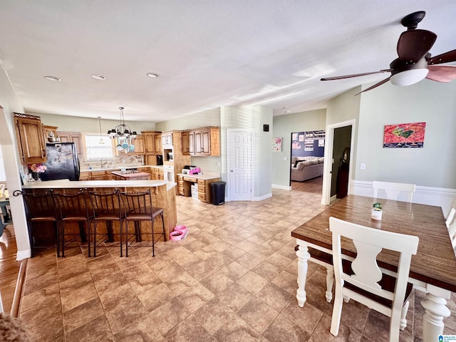 dining space with sink and ceiling fan with notable chandelier