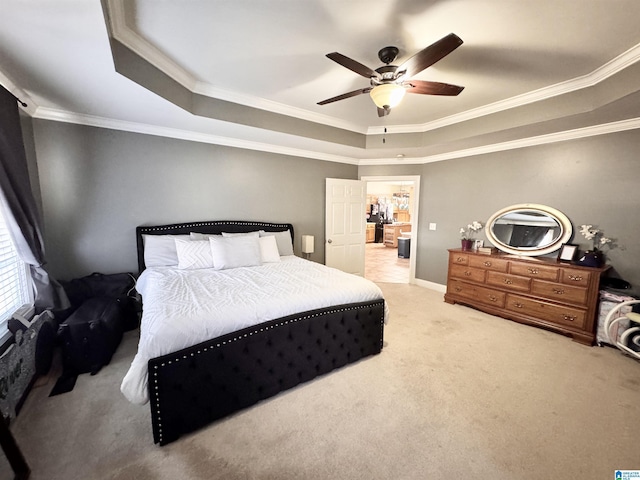 bedroom with ceiling fan, a tray ceiling, light colored carpet, and ornamental molding