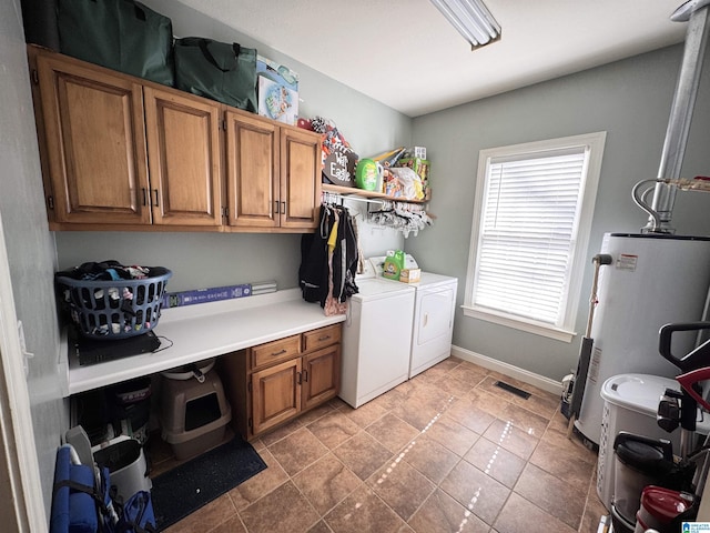 laundry area featuring cabinets, gas water heater, and washing machine and clothes dryer