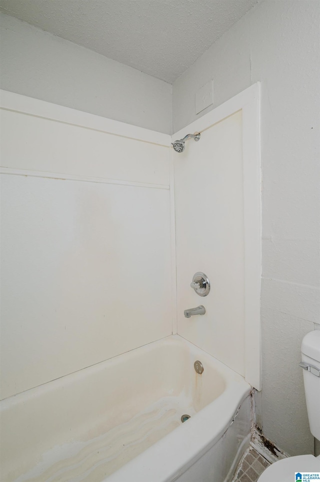 bathroom featuring bathtub / shower combination, a textured ceiling, and toilet